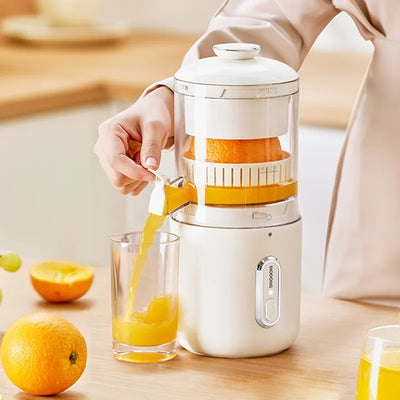 Person using a manual juicer to extract juice from oranges, with a glass of orange juice on a wooden surface.