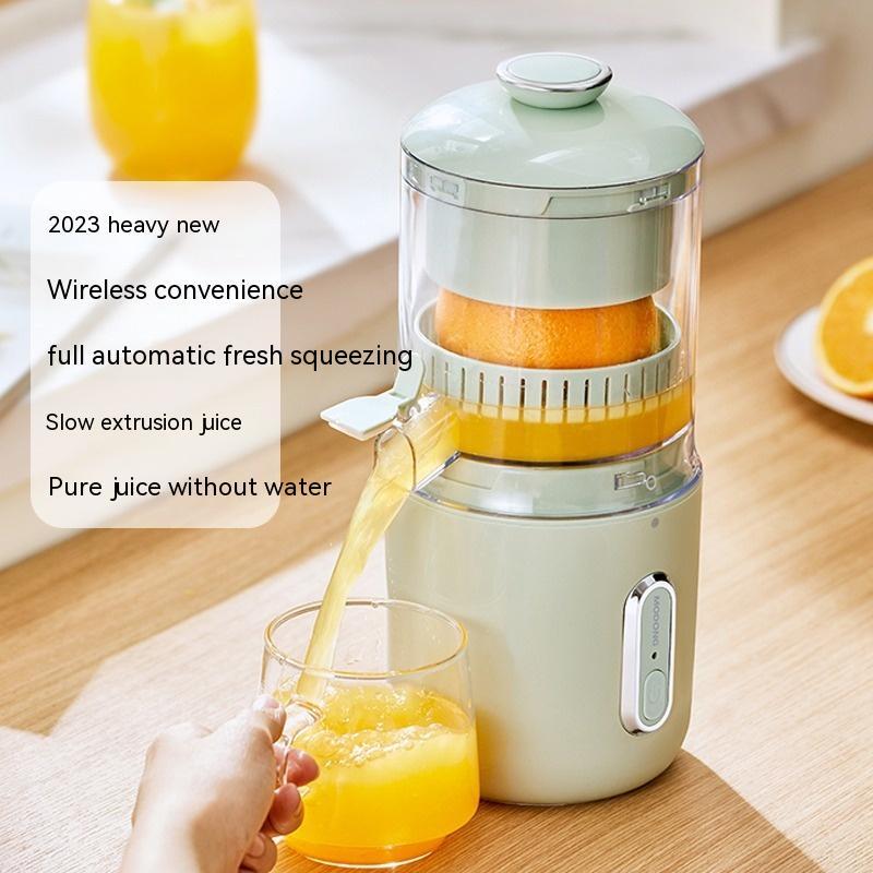 Electric citrus juicer squeezing an orange with a glass of freshly squeezed juice on a wooden table.