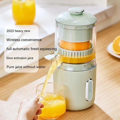 Electric citrus juicer squeezing an orange with a glass of freshly squeezed juice on a wooden table.