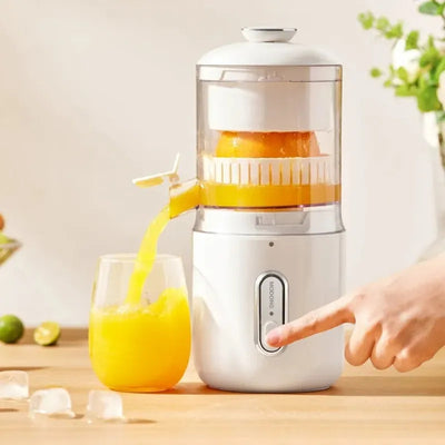 Juicer with a glass of orange juice on a wooden surface